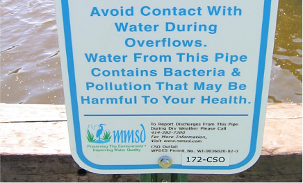 Sign posted near a combined sewer overflow pipe that reads, “Avoid contact with water during overflows. Water from this pipe contains bacteria and pollution that may be harmful to your health.”